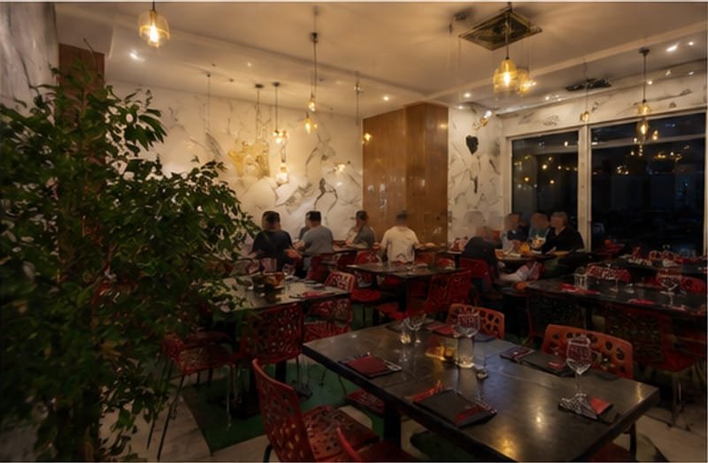 Salle du restaurant en soirée, tables dressées sous les suspensions dorées